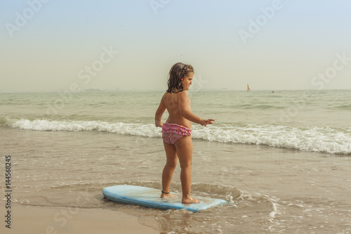 Rear view girl practice surf board in the seashore of the beach. Sunset