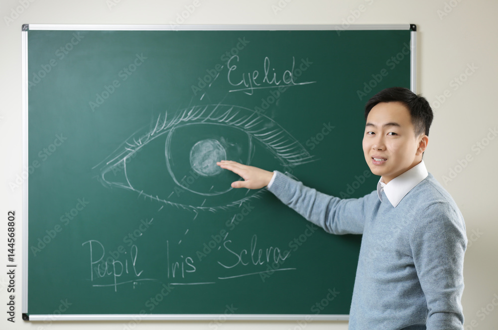 Handsome young Asian teacher near blackboard