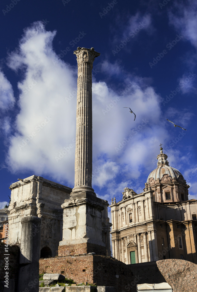 Column of Emperor Phocas in Roman Forum with ancient triumphal arch and baroque church