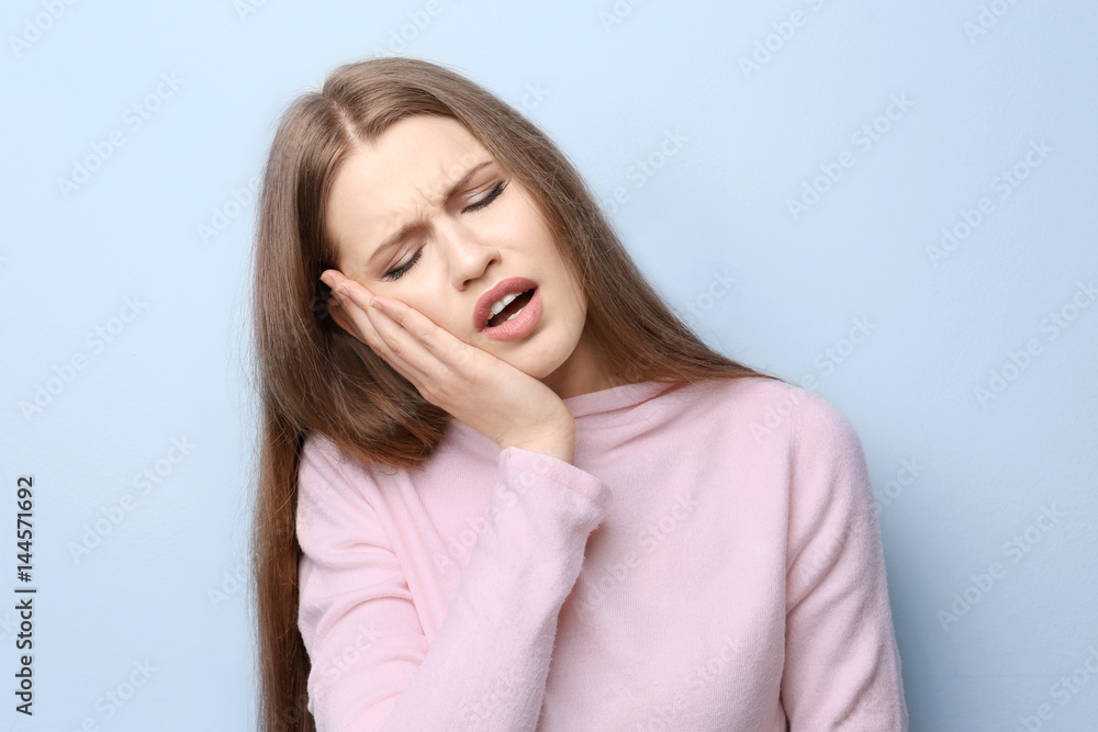 Young woman suffering from toothache on light background Young woman suffering from toothache on light background