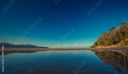 Colorful sky and the ocean smooth reflection in morning time before sunrise. Ocean simple beach panorama. Thailand
