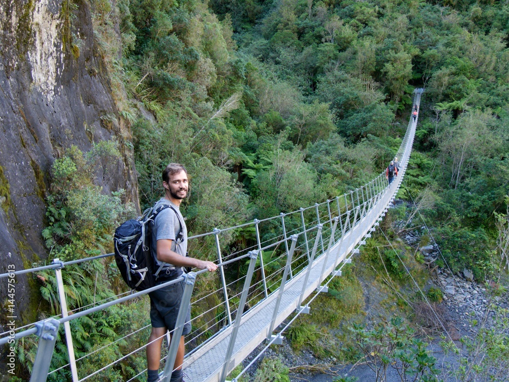 Naklejka premium Male hiker standing on swing bridge