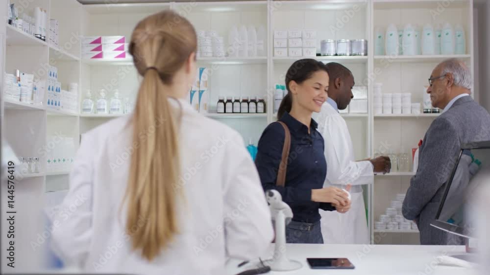 Team of staff working & serving customers in a chemist shop Team of staff working & serving customers in a chemist shop
