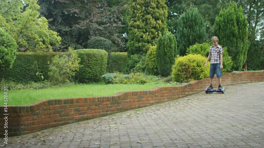 Young boy playing on motorized hover board in the garden at home. Young boy playing on motorized hover board in the garden at home.