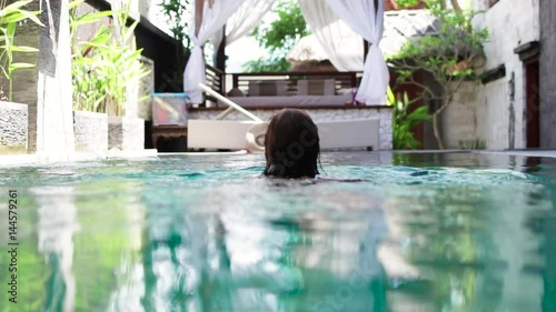 Attractive young caucasian female enjoying leisure time in her swimming pool on a luxury villa, tropical island Bali, Indonesia. Slow motion.