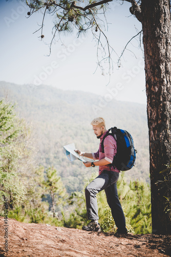 Hiker with map and big traveling backpack traveling to the mountain.