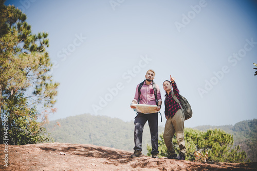 Young tourist couple traveling on holidays in mountain looking at map in search of attractions. Travel concept.