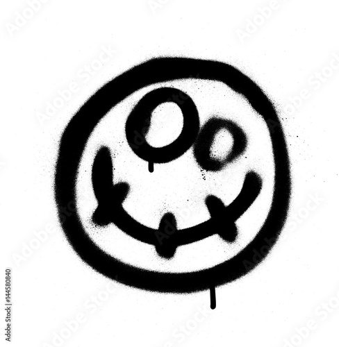 Graffiti scary happy emoji sprayed in black on white