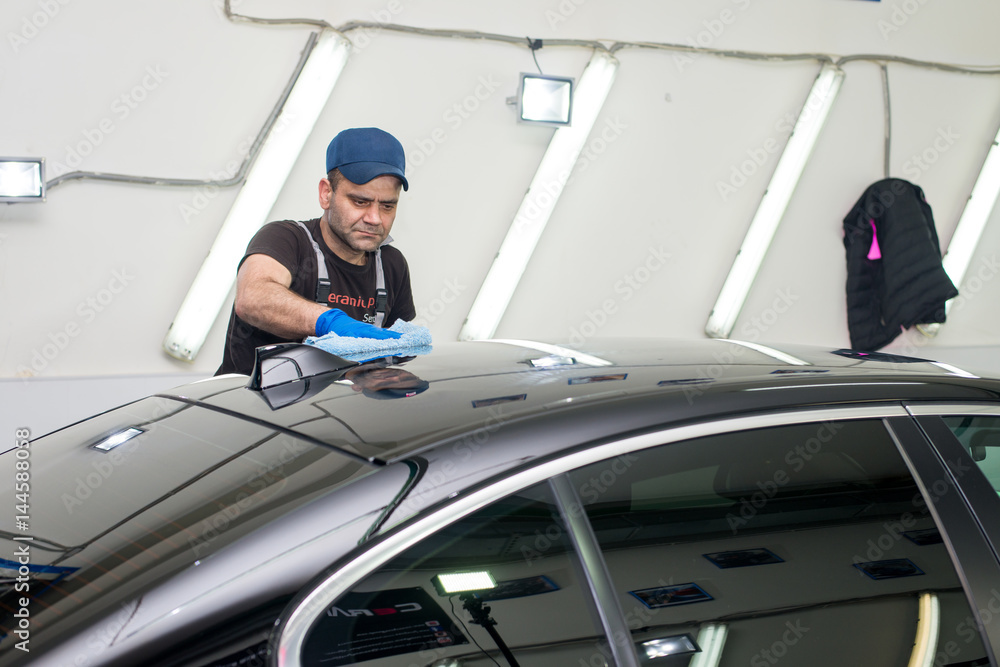 A man polishes a black car A man polishes a black car