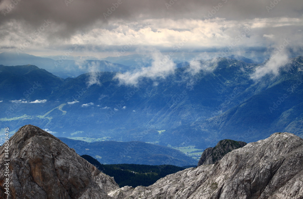 Haze, clouds over Bohinj Valley, Bohinj Range, Julian Alps, Slovenian Prealps in the background, and the pointed rocky Miseljski Konec peak, from Kanjavec, Triglav National Park, Slovenia, Europe