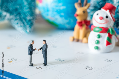 business miniature figures people handshaking agreement on 31 day calendar and christmas ornamental background