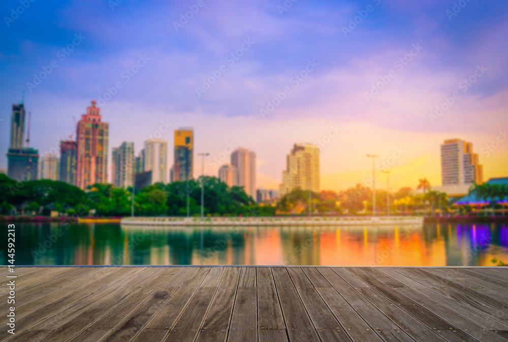 Obraz premium Wooden floor with blurred abstract background of Benchakitti Park at sunset sky in Bangkok, Thailand.