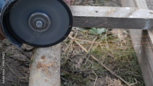 Wallpaper Mural Side view of cutting old rusted iron pipe with an angle grinder outdoors Torontodigital.ca