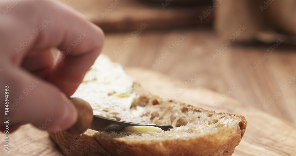 female teen hand spreads butter on slice of rustic bread, 4k photo