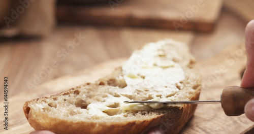 female teen hand spreads butter on slice of rustic bread, 4k photo