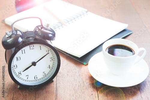 Workspace with alarmclock coffee cup and notebook on wooden table