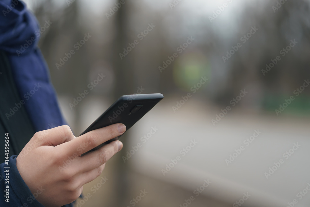 female teen hand using smartphone outddor on empty town street in spring morning, closeup photo female teen hand using smartphone outddor on empty town street in spring morning, closeup photo