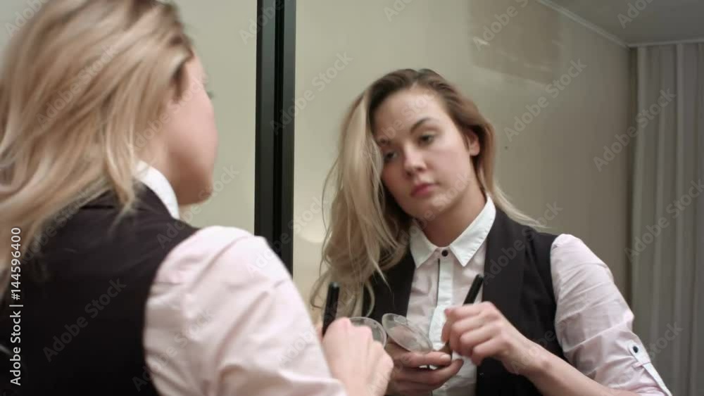 Young beautiful woman applying make up infront of a mirror Young beautiful woman applying make up infront of a mirror