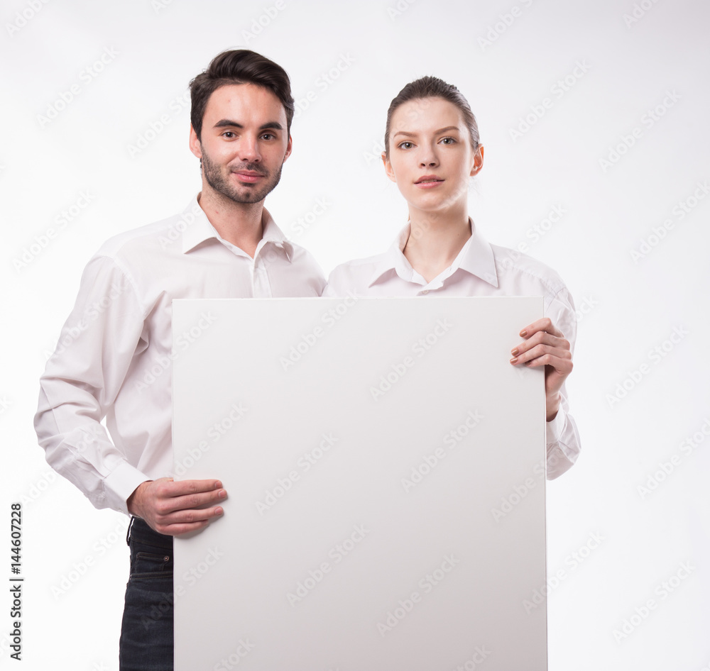 Young happy couple showing presentation pointing on placard over gray background Young happy couple showing presentation pointing on placard over gray background