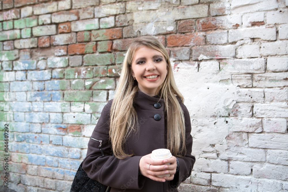 portrait of a smiling Young stylish woman drinking coffee to go in a city street in the morning portrait of a smiling Young stylish woman drinking coffee to go in a city street in the morning