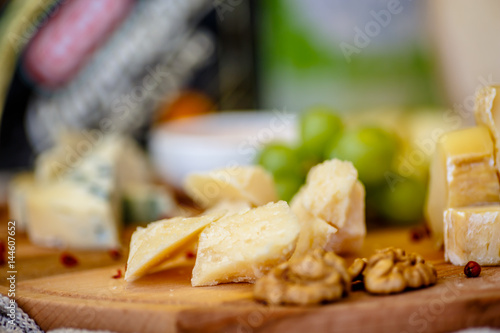 Different types of Italian cheeses (Parmesan, Gorgonzola, Roquefort) are on the Board. Macro.