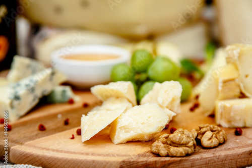 Different types of Italian cheeses (Parmesan, Gorgonzola, Roquefort) are on the Board. Macro.
