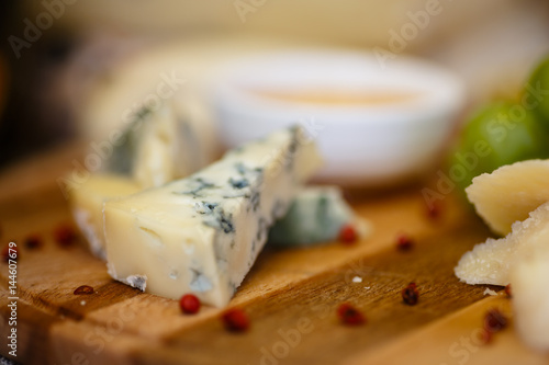 Different types of Italian cheeses (Parmesan, Gorgonzola, Roquefort) are on the Board. Macro.