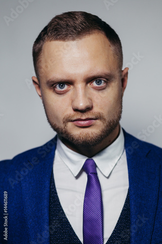 Portrait of serious fashionable handsome man in blue suit looking at camera