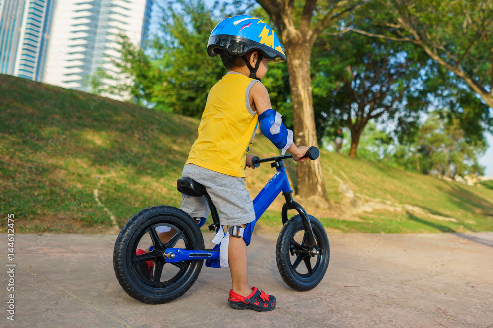 Obraz premium A cute little boy riding a balance bike in the park.