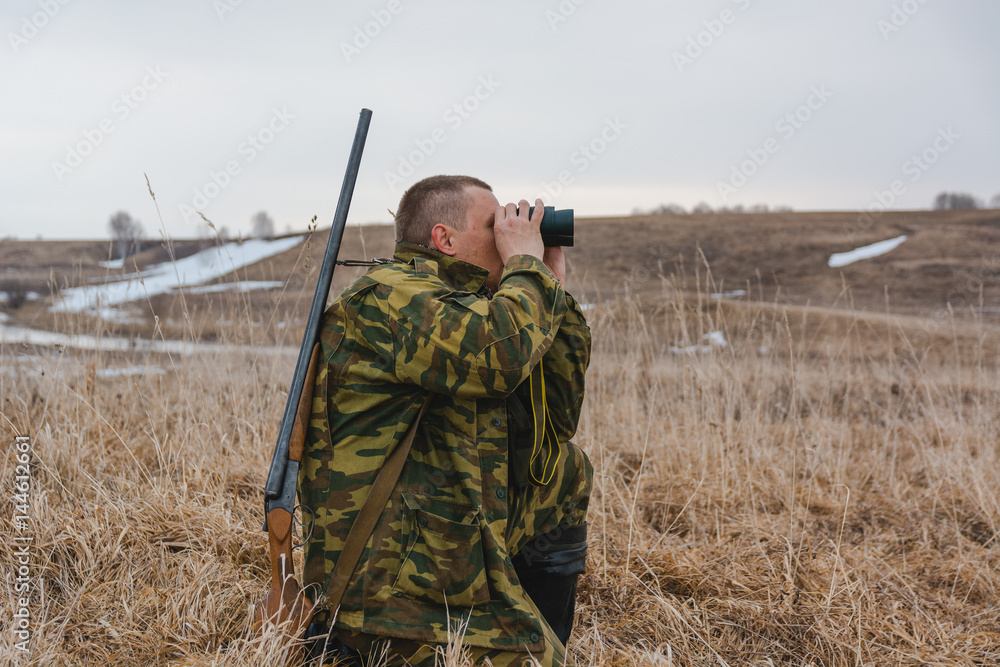 Fototapeta premium The hunter looks in the field-glass. The hunter looks out for a game.