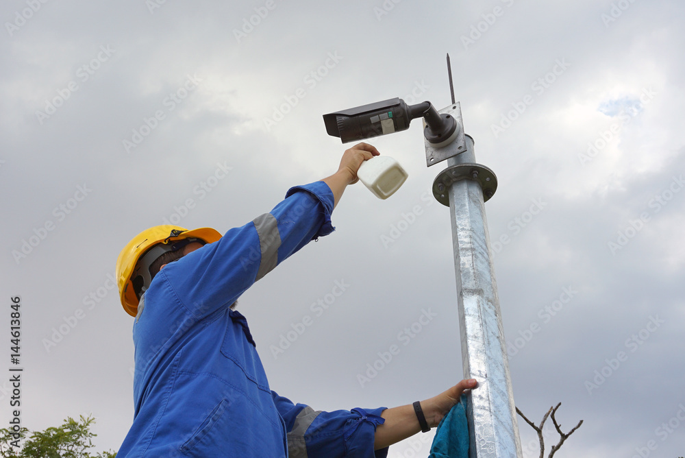 A male worker doing a maintenance work by cleaning and inspecting security camera. A male worker doing a maintenance work by cleaning and inspecting security camera.