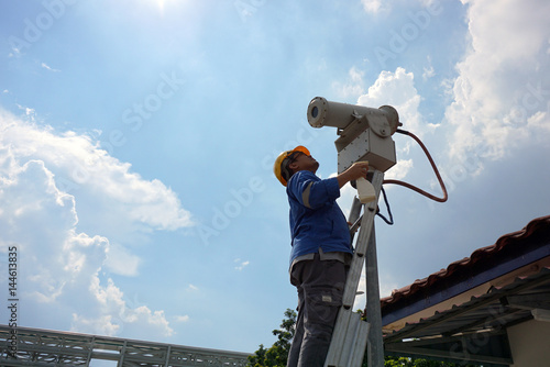 A male worker doing a maintenance work by cleaning and inspecting security camera.