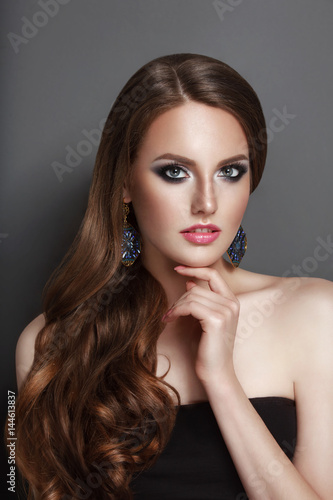 High Fashion Beauty Model Girl en face view with long curly curve brunette hair black corset and huge earings