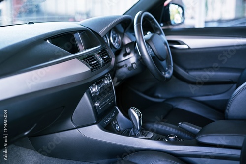 Modern grey and black interior of modern car - shallow DOF. selective focus  close-up details of automatic transmission and gear stick against steering wheel background and dashboard. © KissShot