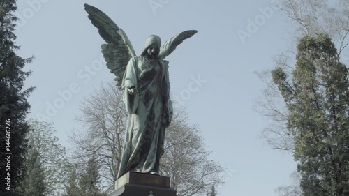 Old tombstone from 20th century with an angel on a sunny spring day.  Pan from right to left. 4K in SLOG3. Medium shot.