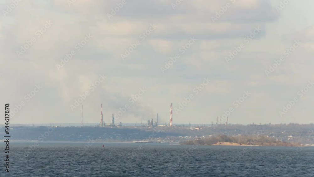 The view from the Volga river in the Factory district of Saratov city. Russia. A river landscape. Factory pipe. Environmental pollution, emissions into the atmosphere. The sky and clouds. Time lapse The view from the Volga river in the Factory district of Saratov city. Russia. A river landscape. Factory pipe. Environmental pollution, emissions into the atmosphere. The sky and clouds. Time lapse