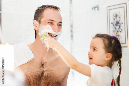Shot of black family having fun in the bathroom with shaving foam. photo