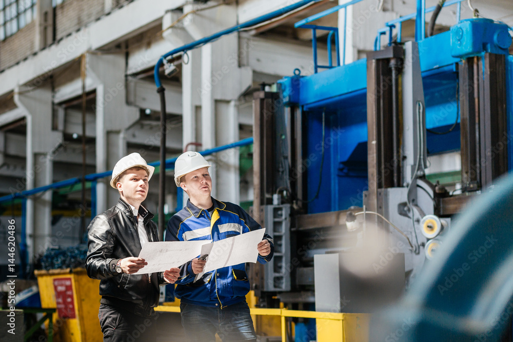 Fototapeta premium A young successful engineer discusses technical documentation with his help in the territory of a modern plant