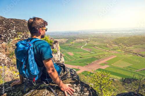 Hiker with backpacks relaxing on top of a mountain and enjoying the view of valley photo