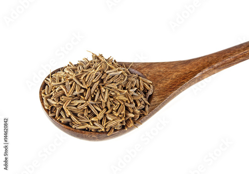 Cumin seeds in wooden spoon, isolated on a white background