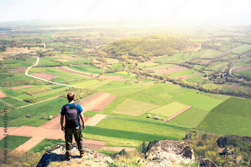 Hiker with backpacks relaxing on top of a mountain and enjoying the view of valley