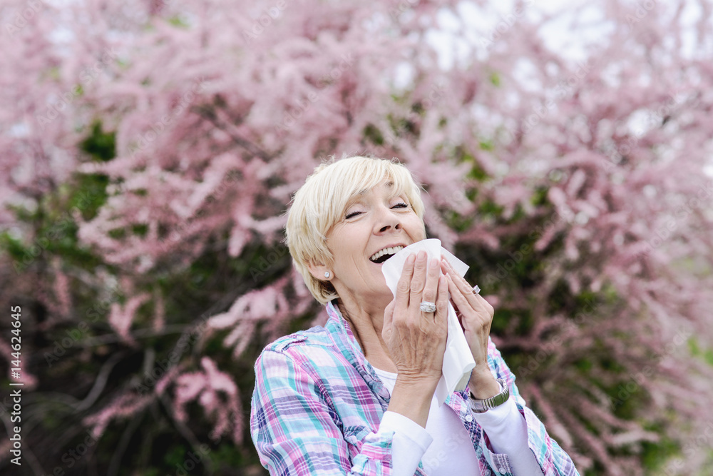 Middle aged blond woman sneezing - seasonal allergy or cold Middle aged blond woman sneezing - seasonal allergy or cold
