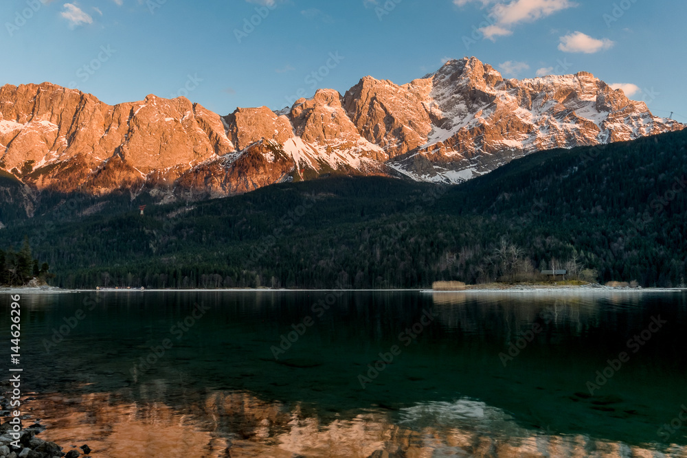 Alpine sunset with beautiful lit mountains in the background and the Eibsee lake in the foreground