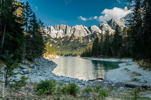 Small alpine fjord with mountains in the background surrounded by a pine forrest.