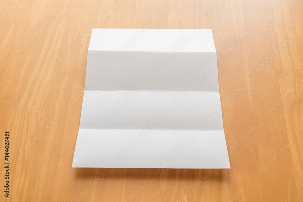 Four fold white template paper with wooden clipboard on wood background Four fold white template paper with wooden clipboard on wood background