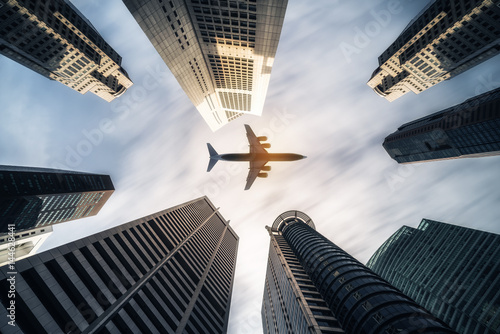 Fotografie Airplane flying over city business buildings, high-rise skyscrapers