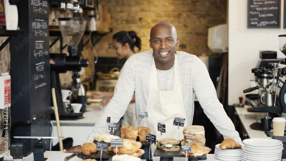 Portrait of friendly smiling worker standing behind counter in coffee shop Portrait of friendly smiling worker standing behind counter in coffee shop