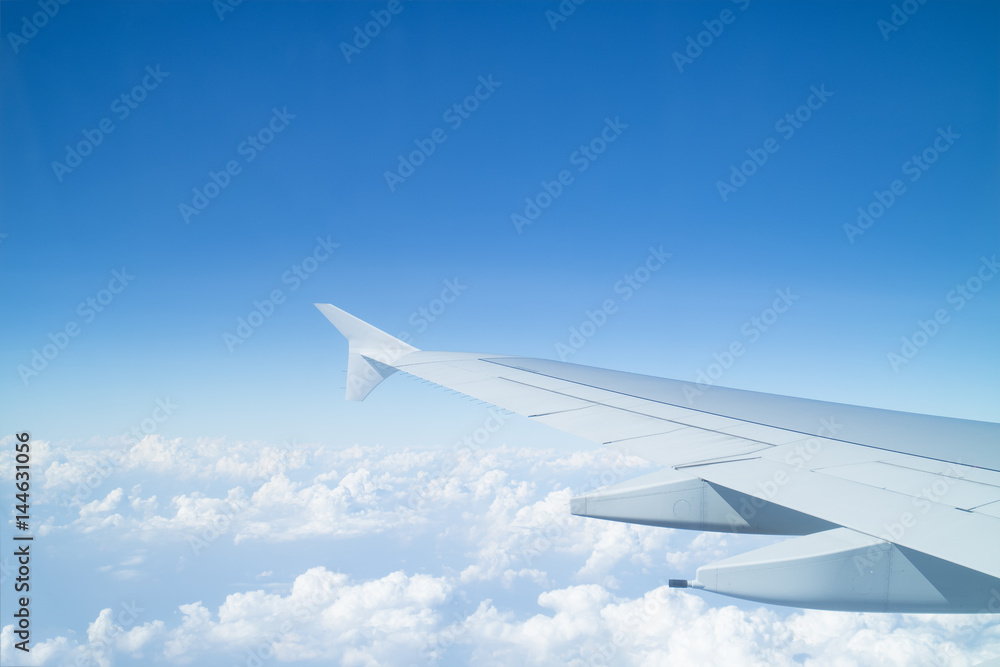 Airplane wing above cloud seen through window