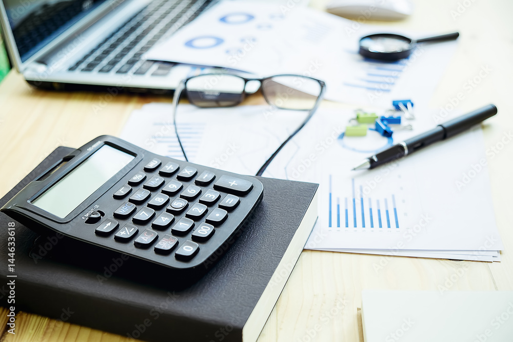 calculator and pen glasses and with Business report financial accounting graphs analysis calculator and pen glasses and with Business report financial accounting graphs analysis