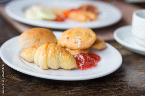 Fresh Croissants with strawberry jam on rustic wooden background. Selective focus